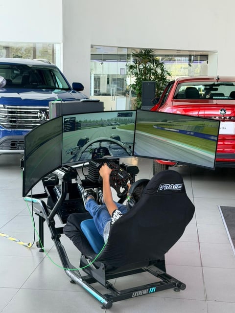 Person using a racing simulator with steering wheel and curved monitor display in a car showroom with Volkswagen vehicles in background