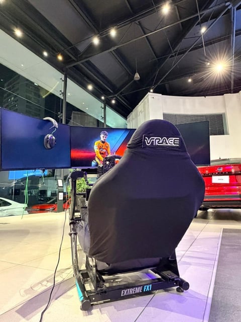VRace gaming chair on display at a tech showroom with screens and gaming equipment in the background