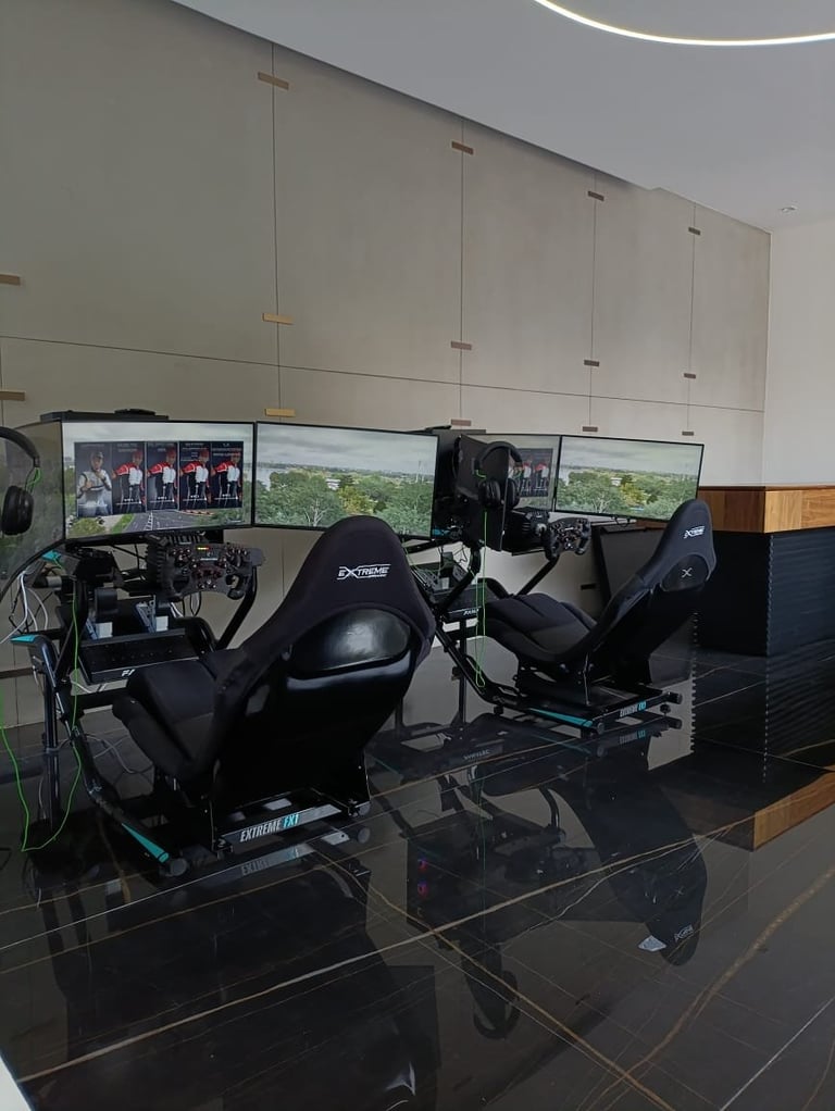 Racing simulator setup with two gaming chairs facing multiple screens displaying racing game scenes in a modern facility